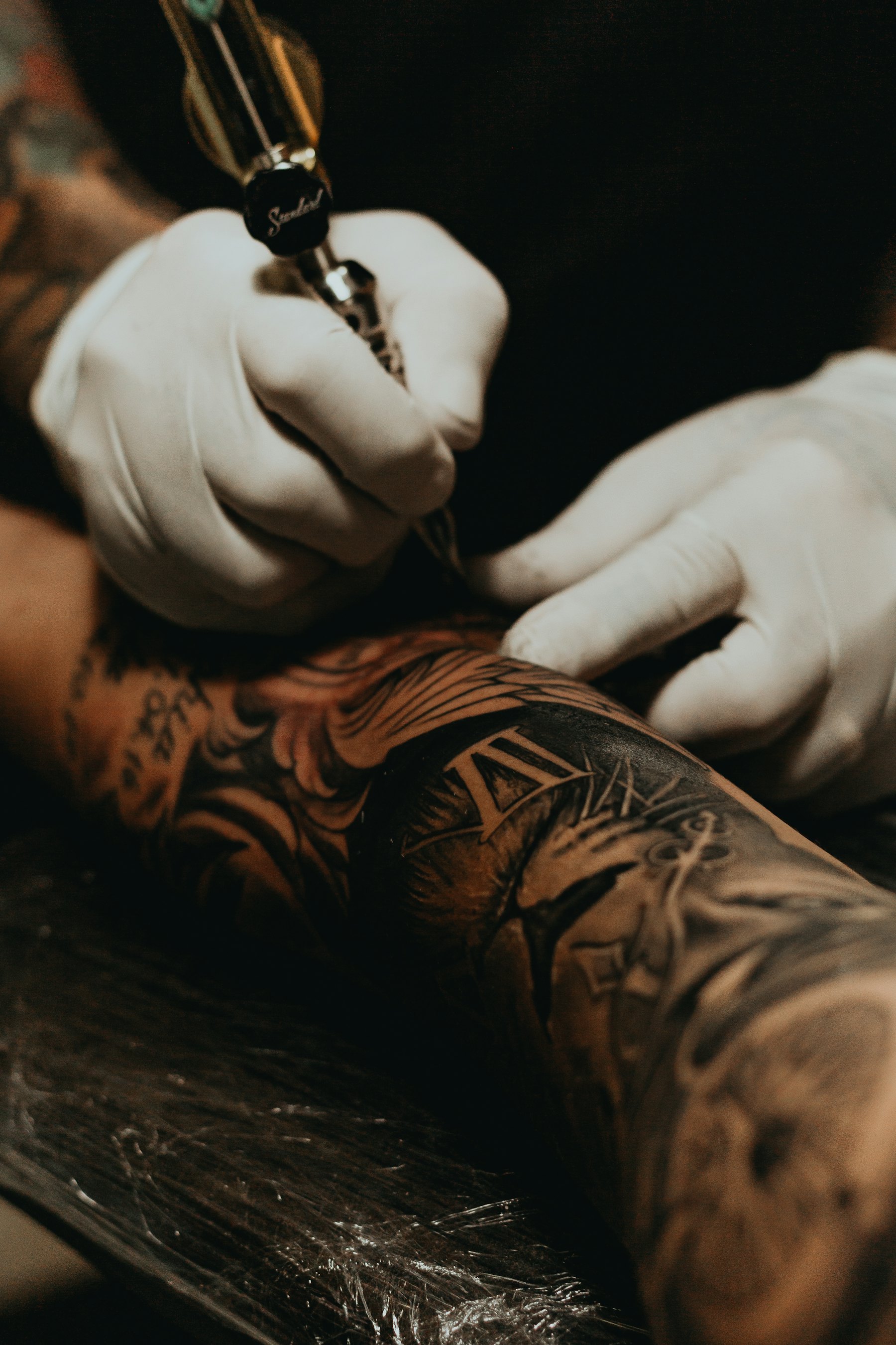 Tattooer working on a client's forearm